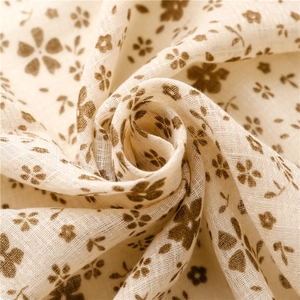Dettaglio macro della sciarpa in cotone e lino beige con motivi floreali marroni