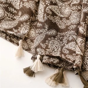 Dettaglio macro della sciarpa in cotone paisley marrone con nappe intrecciate e morbide