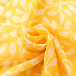 Détail d'une écharpe en coton jaune montrant la texture douce et le motif de feuilles
