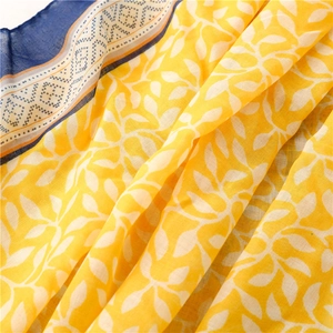 Gros plan du foulard en coton jaune avec feuilles blanches et bordure bleue