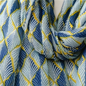 Detailtextur aus blauem und ingwerfarbenem Blattmuster auf leichtem Baumwollschal
