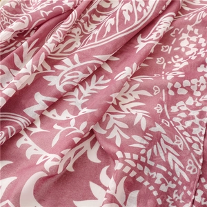 Close-up of soft dusty pink scarf featuring white botanical leaf patterns and tassels