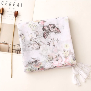 Detail of white scarf featuring pink rose patterns, butterfly prints and fringe edges
