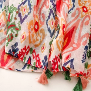 Detailed close-up of vibrant Ikat print scarf featuring colorful fringe tassel trim
