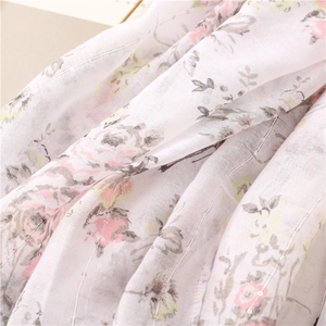 Detail of lightweight white scarf featuring floral prints and silver metallic thread accents