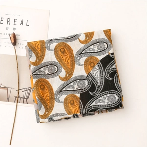 Détail à plat d'une écharpe en coton et lin avec motif paisley orange et noir