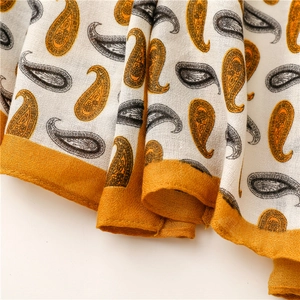 Gros plan du motif Paisley orange et noir sur une écharpe en lin texturé