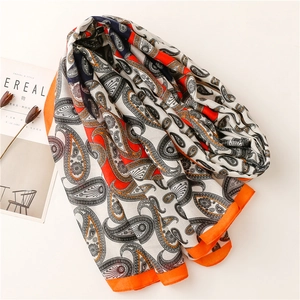 Détail d'une écharpe bohème à motif paisley avec bordure orange et texture lin