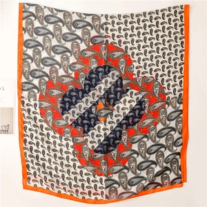Détail d'un foulard carré à motif paisley avec bordures orange et motifs floraux