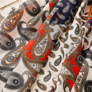 Détail d'une écharpe à motif cachemire avec des tons crème, rouge et bleu et des plis doux