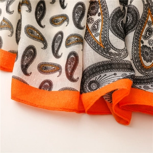 Détail de l'écharpe à motif cachemire montrant la texture et le bord orange vif