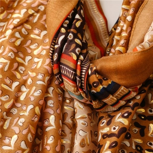 Detail of soft earth tone scarf featuring gold foil patterns and intricate fringe edges