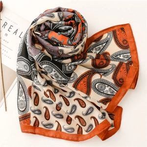 Détail d'un châle à motif paisley avec bordures orange de qualité sur fond blanc
