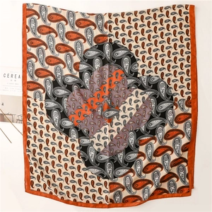 Mise à plat d'un foulard paisley avec bordure orange caramel près d'un magazine