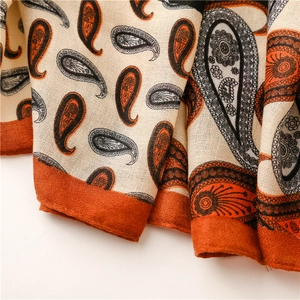 Détail d'une écharpe à motif cachemire aux tons orange chauds et texture tissée fine