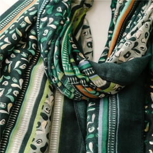 Detail of dark green bohemian scarf featuring gold foil prints and soft ethnic patterns