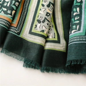 Detail of soft dark green scarf with colorful geometric patterns and fringe edges