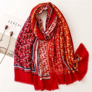 Close-up of vibrant red linen-feel scarf with gold foil accents and tassel edges