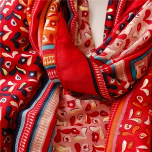 Close-up of soft cotton-linen scarf featuring red floral patterns and gold foil detail
