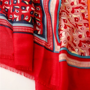 Close-up of soft red and pink scarf with gold foil paisley print and frayed edges