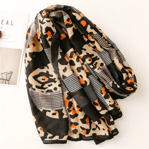 Detail of leopard print and geometric pattern splicing on a soft orange linen-feel scarf
