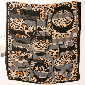 Detail of a leopard print cotton-linen scarf with geometric patterns and orange accents