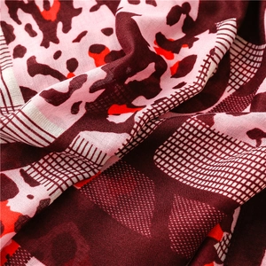 Macro detail of lightweight scarf fabric with burgundy and orange leopard print