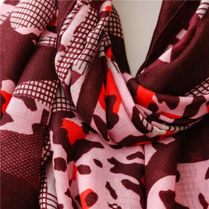 Detail of soft linen-feel scarf showing wine red abstract leopard print and fine texture