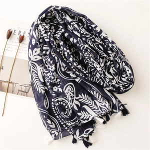 Navy blue floral paisley scarf with tassels shown with elegant lifestyle accessories