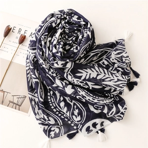 Detail of navy blue bohemian leaf print scarf with cotton tassels and soft fabric texture