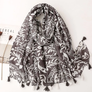 Detail of dark grey cotton linen scarf featuring white bohemian leaf prints and tassels