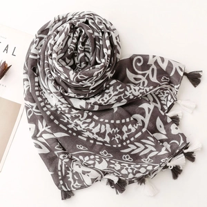 Detail of grey paisley print scarf with soft fringe tassels on a minimalist background