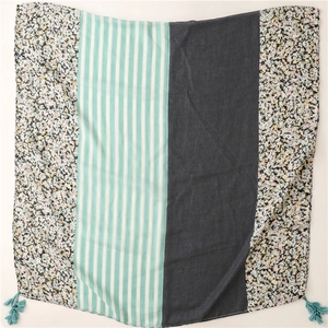 Detail of patchwork scarf featuring floral, stripe, and polka dot patterns with green tassels
