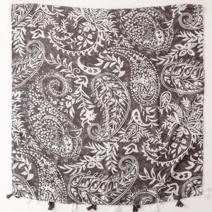 Detail of dark grey paisley print shawl with decorative tassels and textured fabric