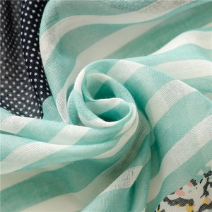 Detail of green striped fabric with blue polka dots and soft cotton tassel texture