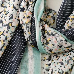 Detail showing mixed patterns of polka dots, florals, and green stripes on cotton scarf