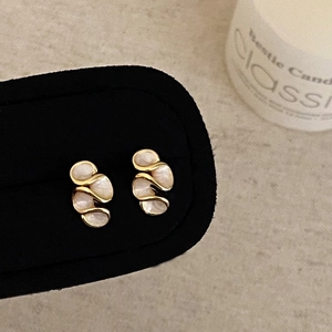 Boucles d'oreilles fleurs ondulées dorées avec émail nacré et zircon sur support noir élégant