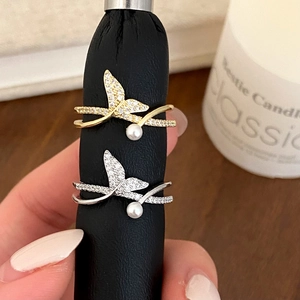 Detailed view of silver and gold fishtail rings with sparkling zircons and white pearls