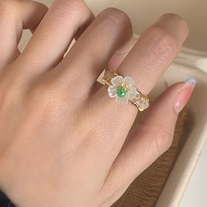 Handcrafted gold wire flower ring with white petals and a green crystal centerpiece