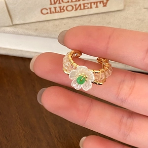 Detail of floral crystal ring with gold wire wrap design and white flower accent