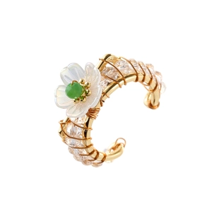 Handcrafted gold wire flower ring with crystals and green bead on a white background