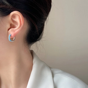 Elegant silver hoop earrings with light blue enamel finish on a female model