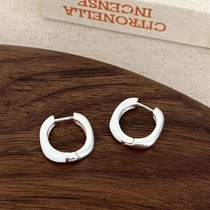 Detail of square silver hoops with white enamel finish on dark wood and book setup