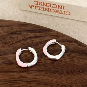 Detailed close-up of pink enamel geometric earrings on a dark wooden display tray