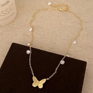 Detailed close-up of gold butterfly pendant and zircon accents on a fine chain