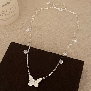 Close-up of silver butterfly pendant necklace with sparkling cubic zirconia on brown board