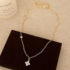 Dettaglio della collana dorata con ciondoli a fiori in zircone e chiusura a moschettone