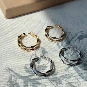 Dettaglio ravvicinato di orecchini a spirale a doppio strato in oro e argento intrecciato