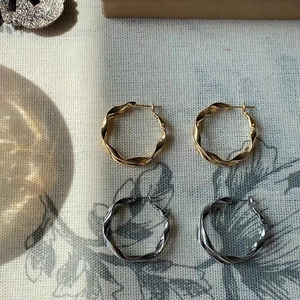 Vista dettagliata di orecchini a cerchio a spirale irregolare color oro e argento