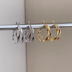 Primo piano di orecchini a doppia spirale intrecciata in finitura oro e argento